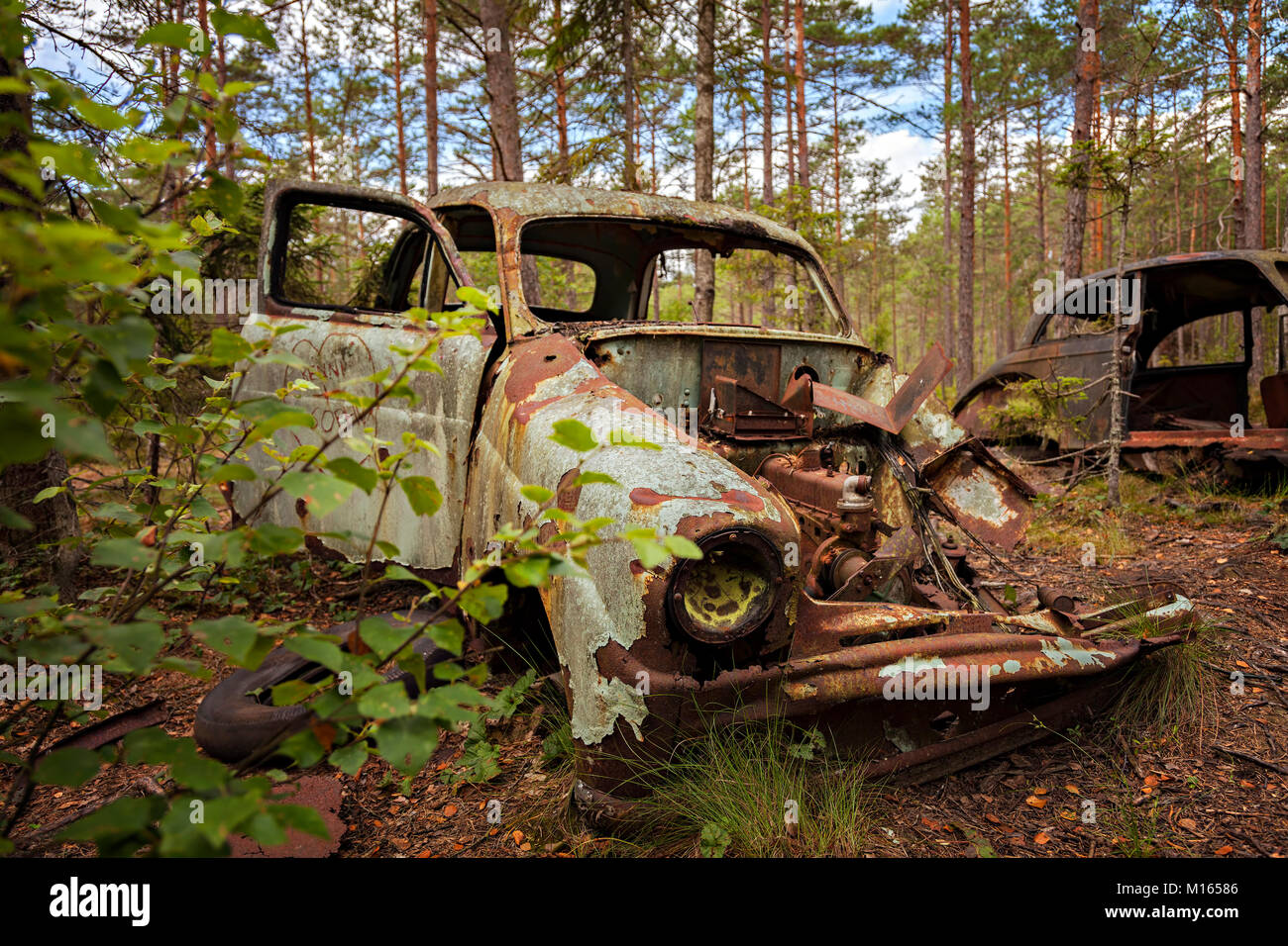 Abbandonato rusty vecchia auto in una foresta. Foto Stock