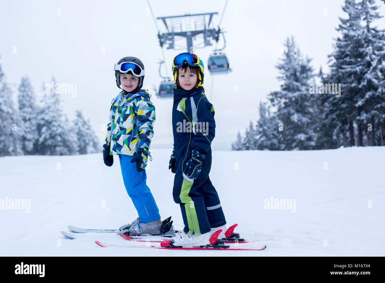 Carino piccolo bambini di età prescolare, ragazzo fratelli in giacche blu, sci felicemente in una giornata di sole in Als Foto Stock