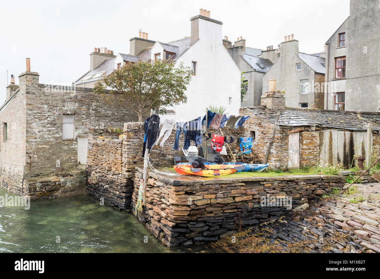 Kayak da mare e muta l'asciugatura sulla linea di lavaggio nel giardino sul lungomare in Stromness, isole Orcadi Scozia, Regno Unito Foto Stock