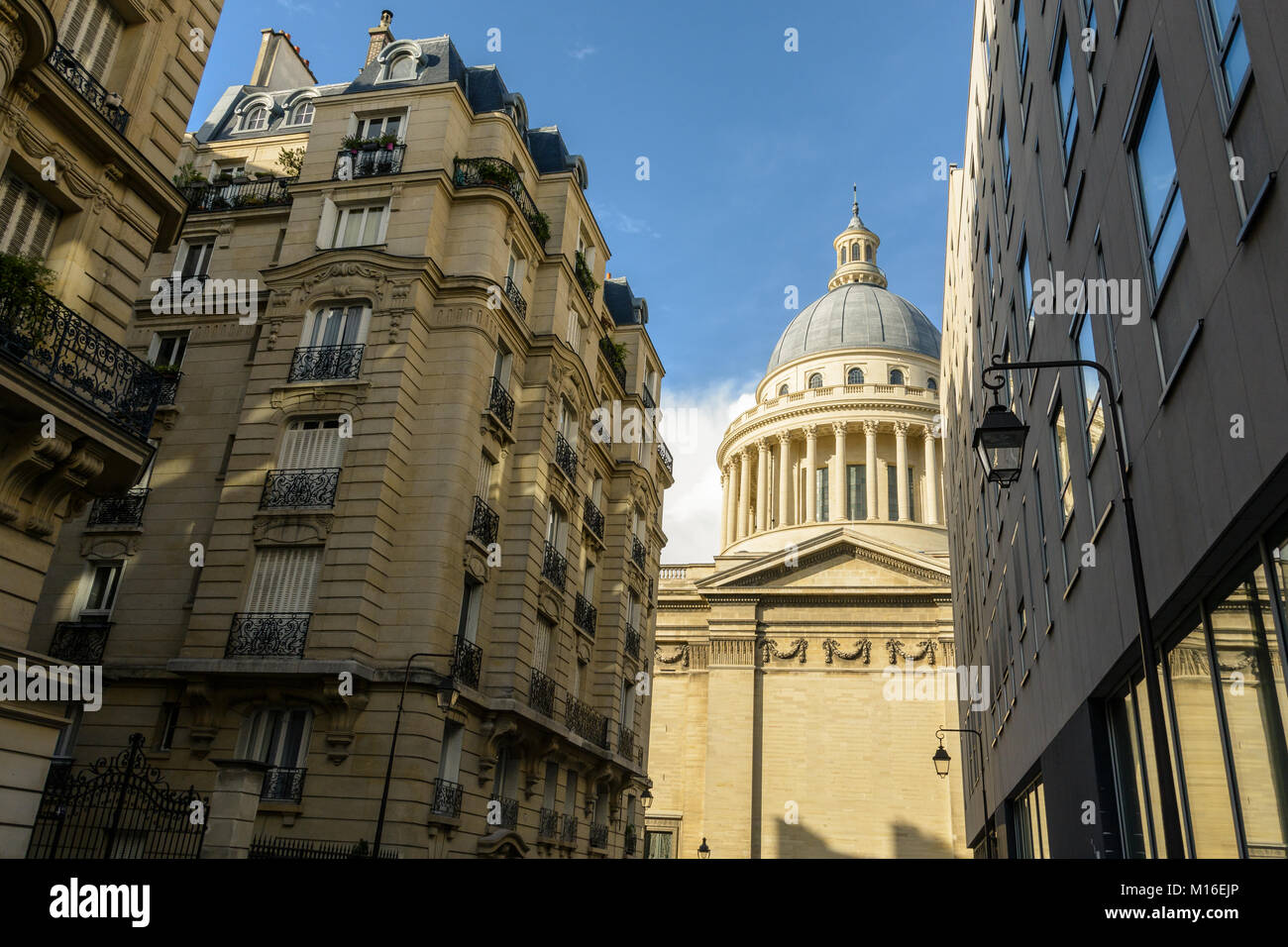 Basso angolo vista laterale della cupola del Pantheon di Parigi a partire da una stretta strada adiacente con classici e moderni edifici Parigini in primo piano. Foto Stock