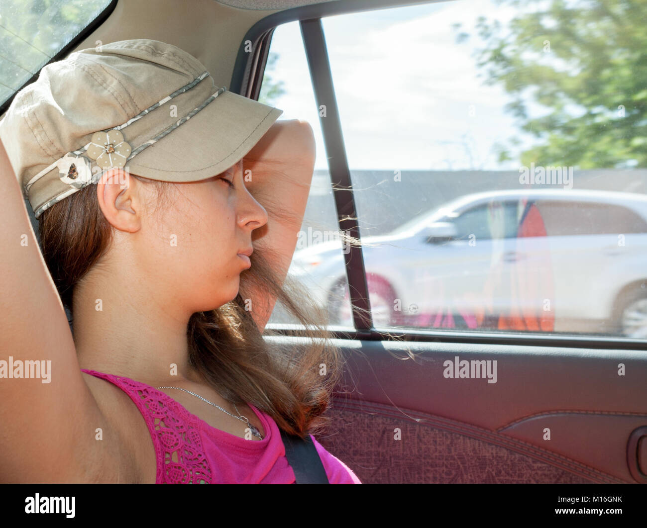La ragazza di kepi è appoggiato con gli occhi chiusi, durante il viaggio in auto. Foto Stock