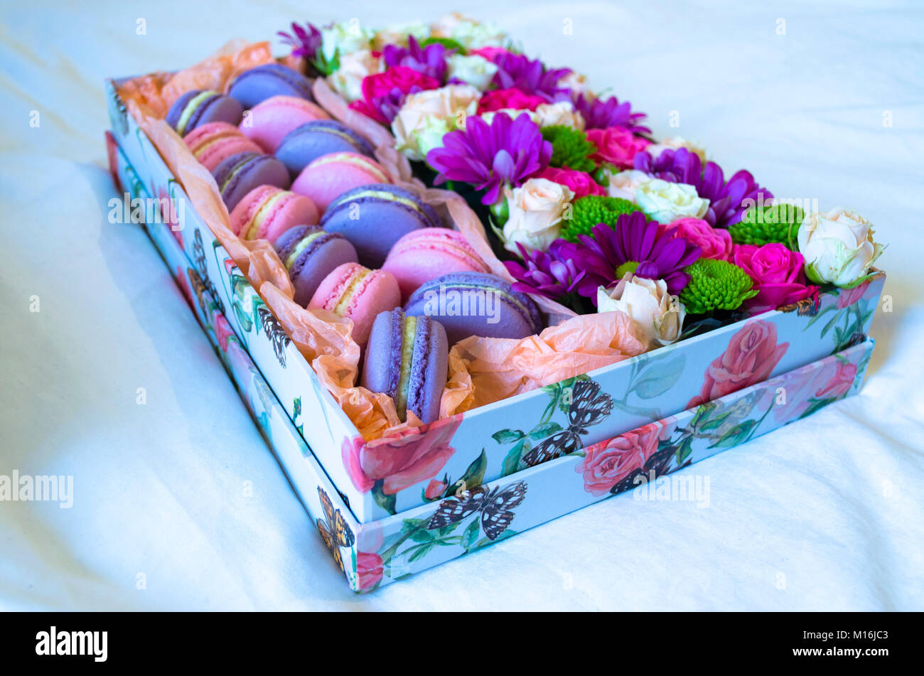 Amaretto francese torta. Viola e rosa amaretti in una scatola con fiori sul letto. Foto Stock