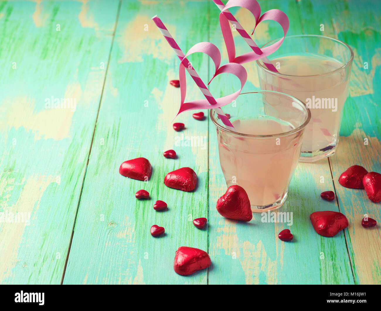 Rosso rubino il succo di pompelmo e forma di cuore cioccolatini su sfondo di legno. Il giorno di San Valentino concetto Foto Stock