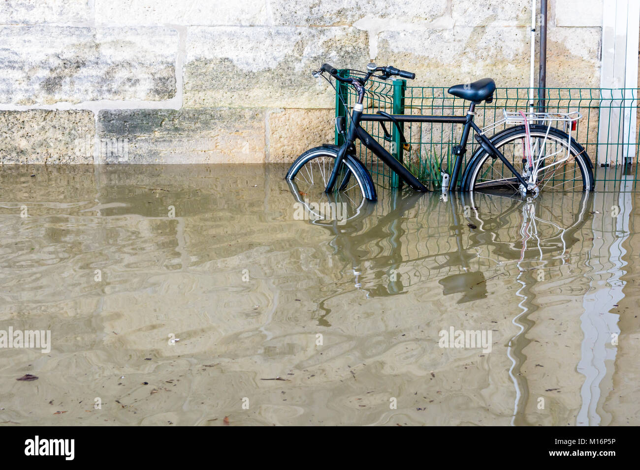 Una bicicletta fissata con un U-lock per una griglia sulle rive della Senna con acqua a metà altezza dopo il fiume gonfio scoppia le sue banche durante un w Foto Stock