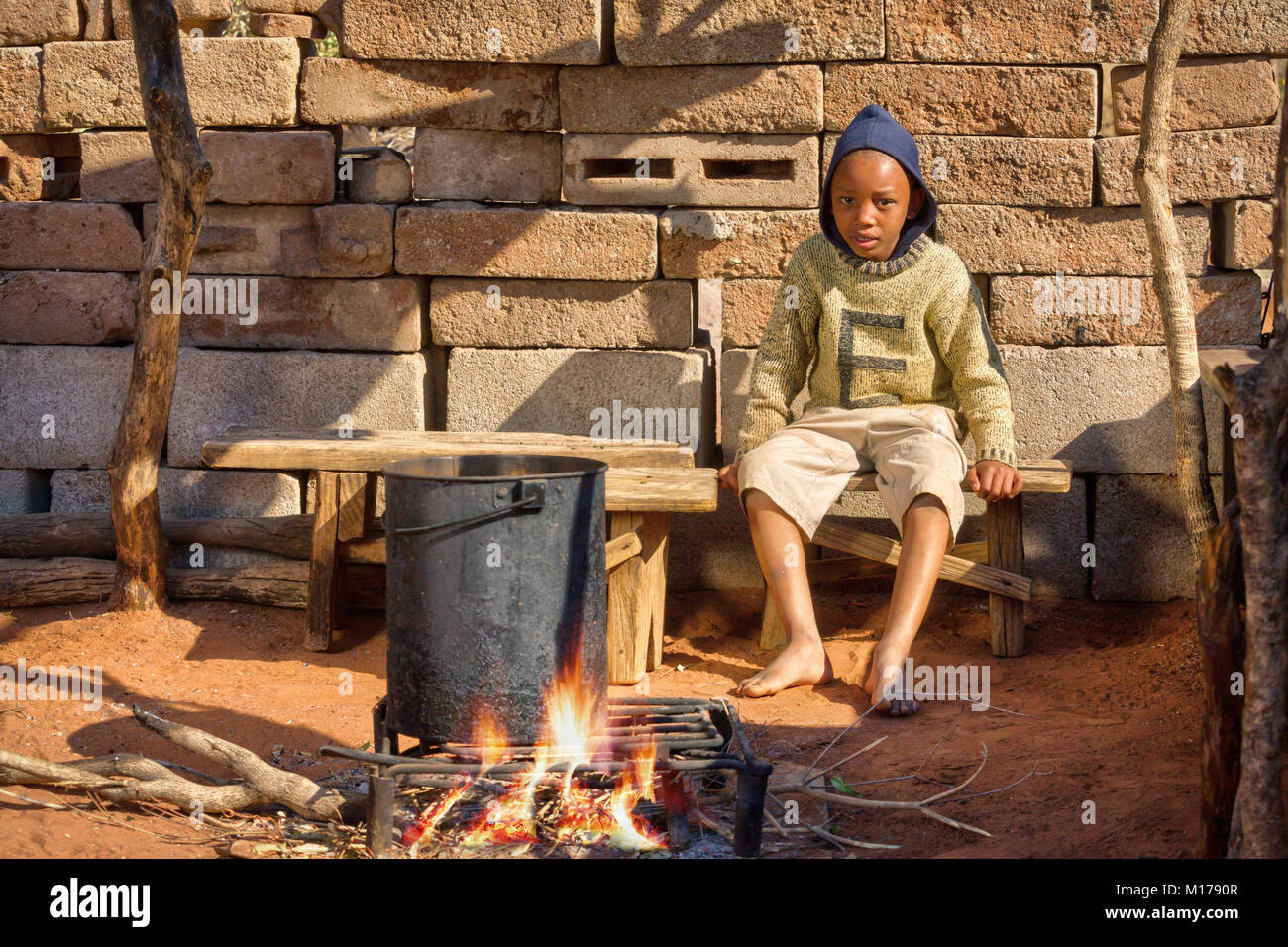 Bambino africano per la cottura all'aperto, guardando la cena, cucina nel borgo, Botswana Foto Stock