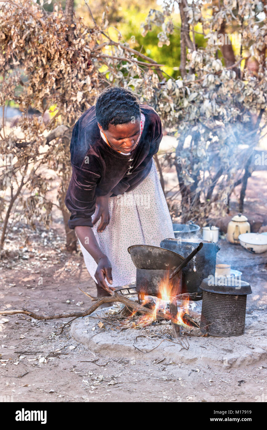 Donna africana cucina cucina all'aperto nel villaggio, Botswana Foto Stock