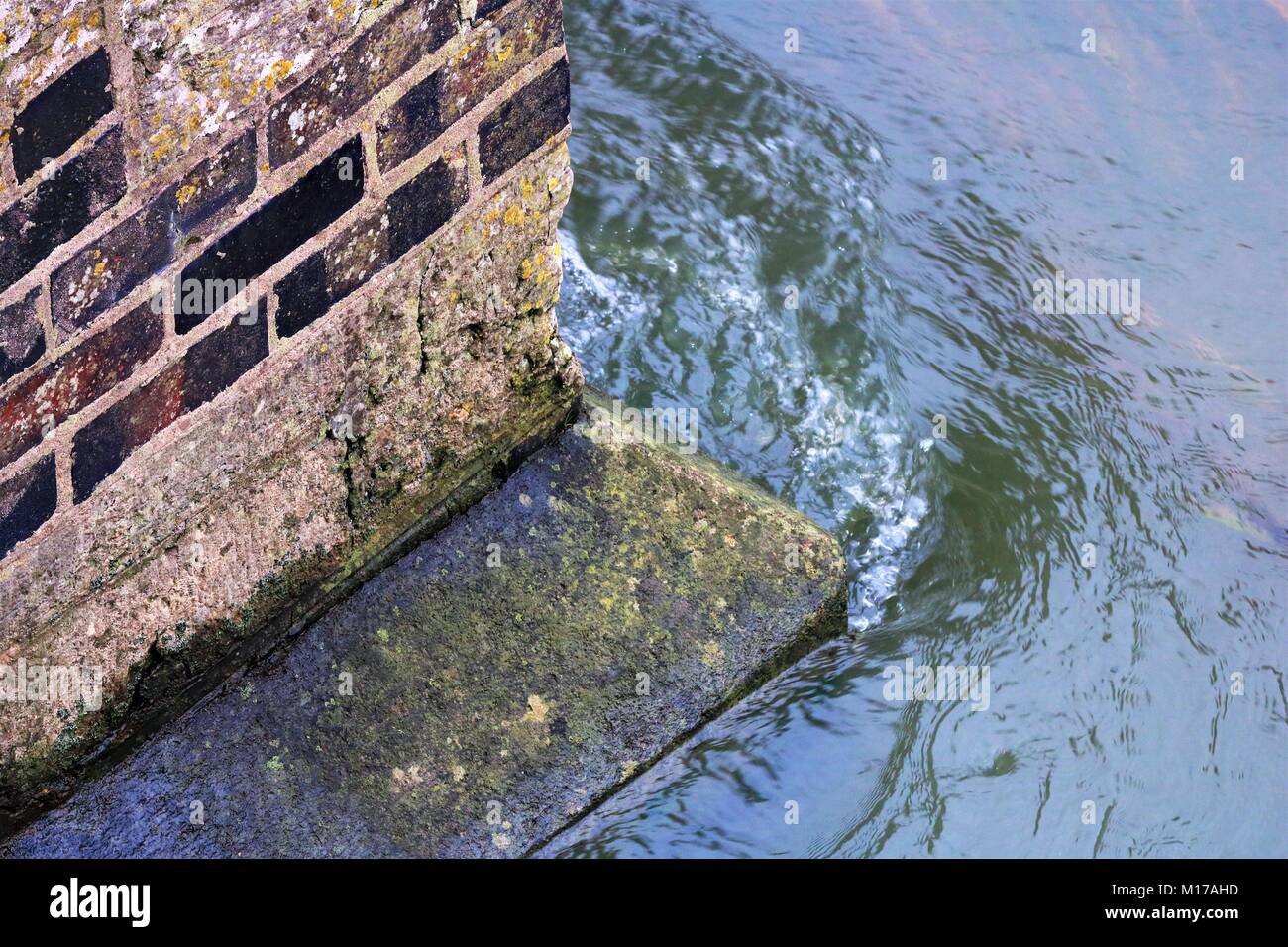 Angolo di visualizzazione di un flusso di acqua che colpisce angolo del pilastro ponte risultante in increspature e bolle in acqua Foto Stock
