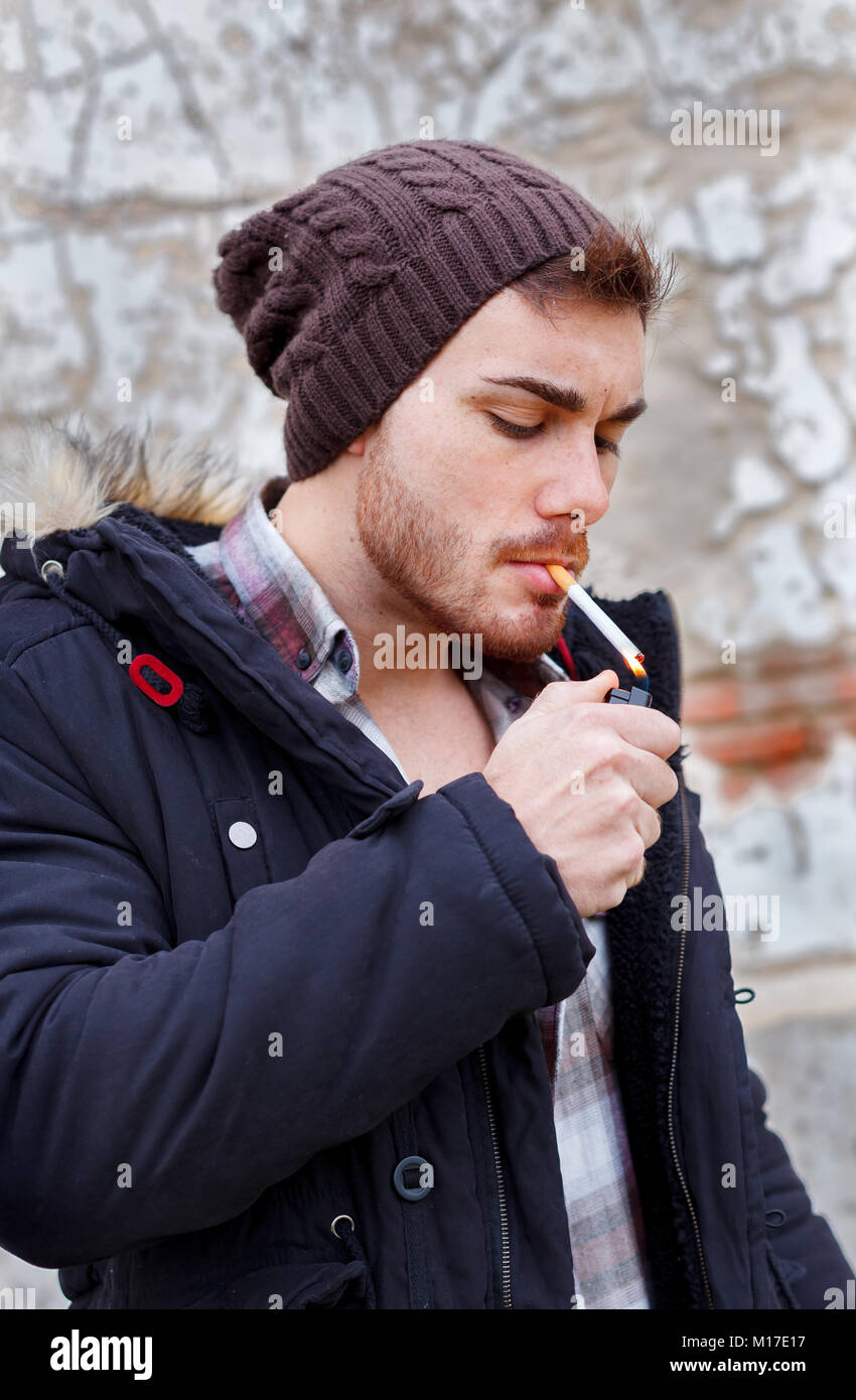 Giovane ragazzo con cappello di lana di fumare in strada Foto stock - Alamy