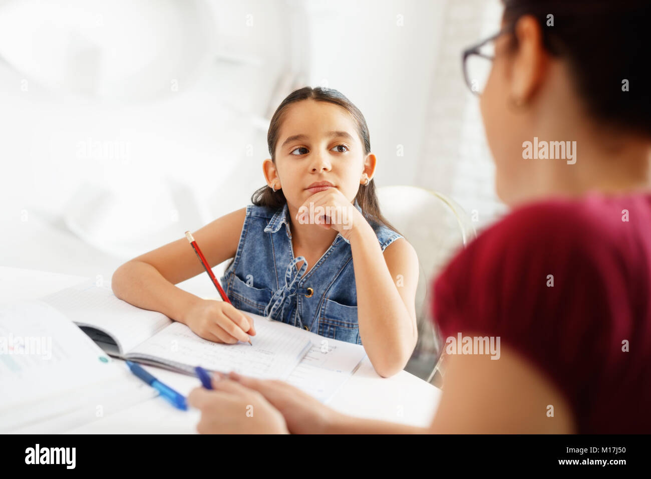 Madre ispanica aiutando ragazza fare scuola compiti a casa Foto Stock