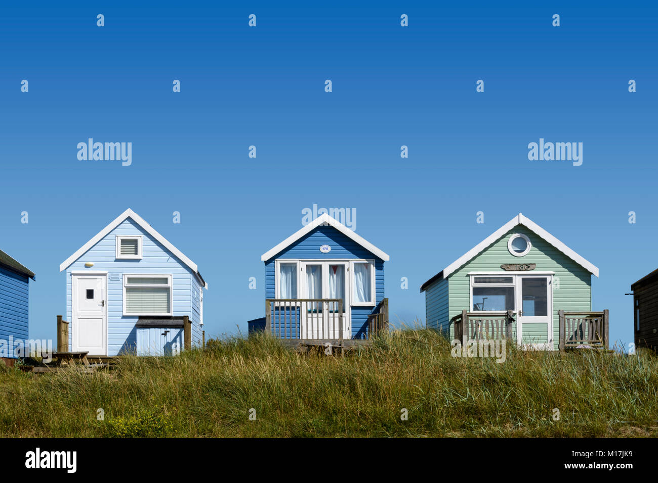 Verniciato colorato cabine in legno tra le dune di sabbia a Mudeford allo spiedo, vicino a Christchurch, Dorset, England, Regno Unito, Europa Foto Stock