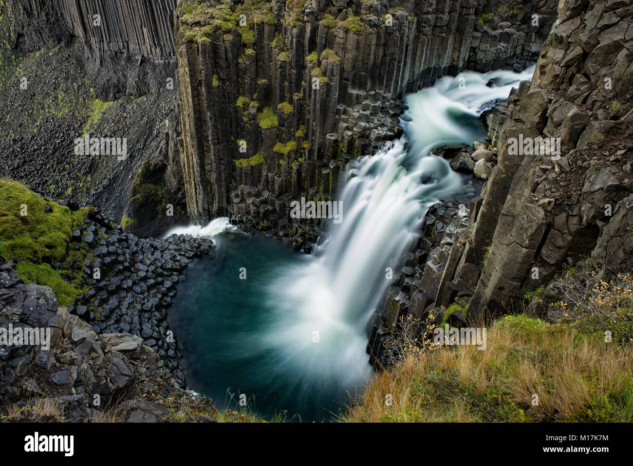 Litlanesfoss cascata e il fiume che scorre tra le colonne di basalto su un nuvoloso giorno di autunno, Islanda Orientale Foto Stock