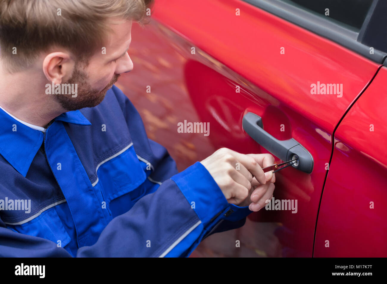 Close-up di una mano umana apertura Red auto della porta con Lockpicker Foto Stock