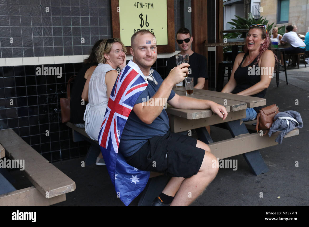 Un uomo celebra con i vostri amici in Australia giorno drappeggiati nella bandiera australiana al pub su Broadway Sydney. Foto Stock