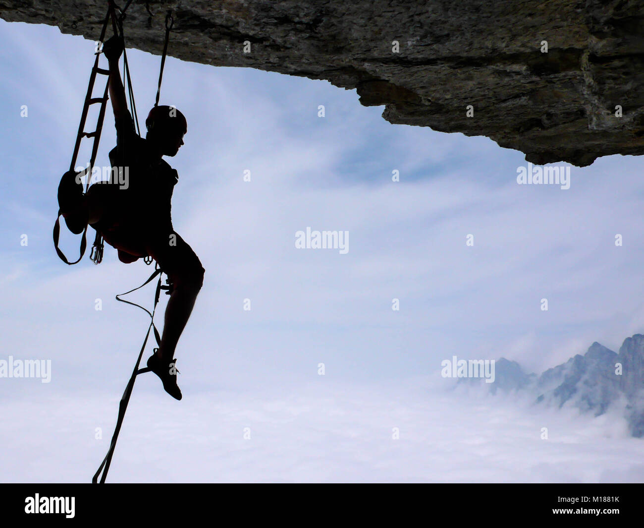 Maschio di scalatore di arrampicata di aiuto una tecnica difficile tetto sovrastante Foto Stock