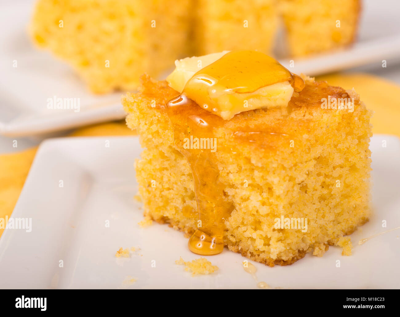 Pezzo di pane appena sfornato cornbread con burro e miele gocciolare fuori dalla parte superiore Foto Stock