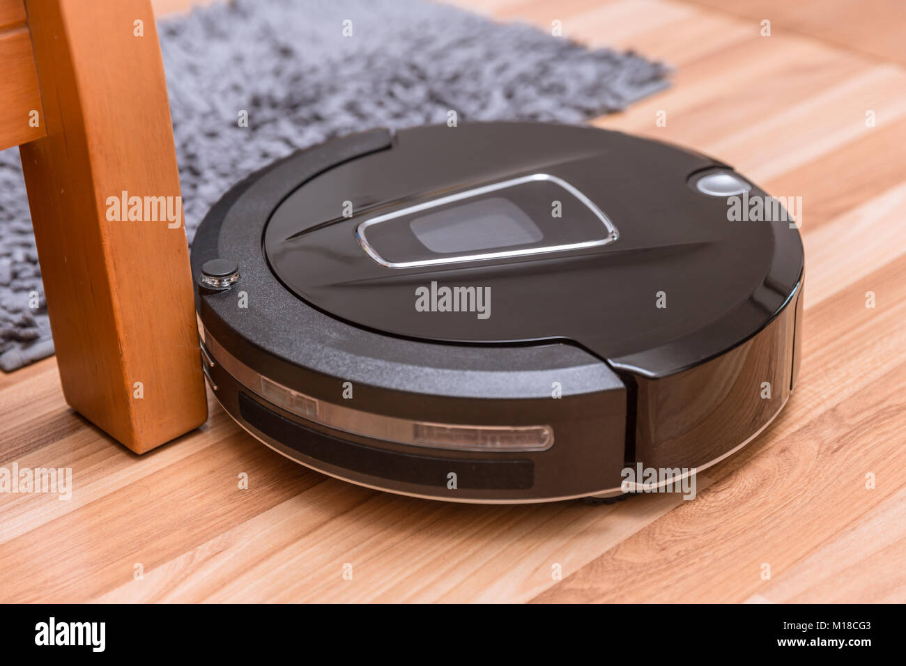 Robot aspirapolvere sul laminato pavimento in legno con pulizia moquette Foto Stock