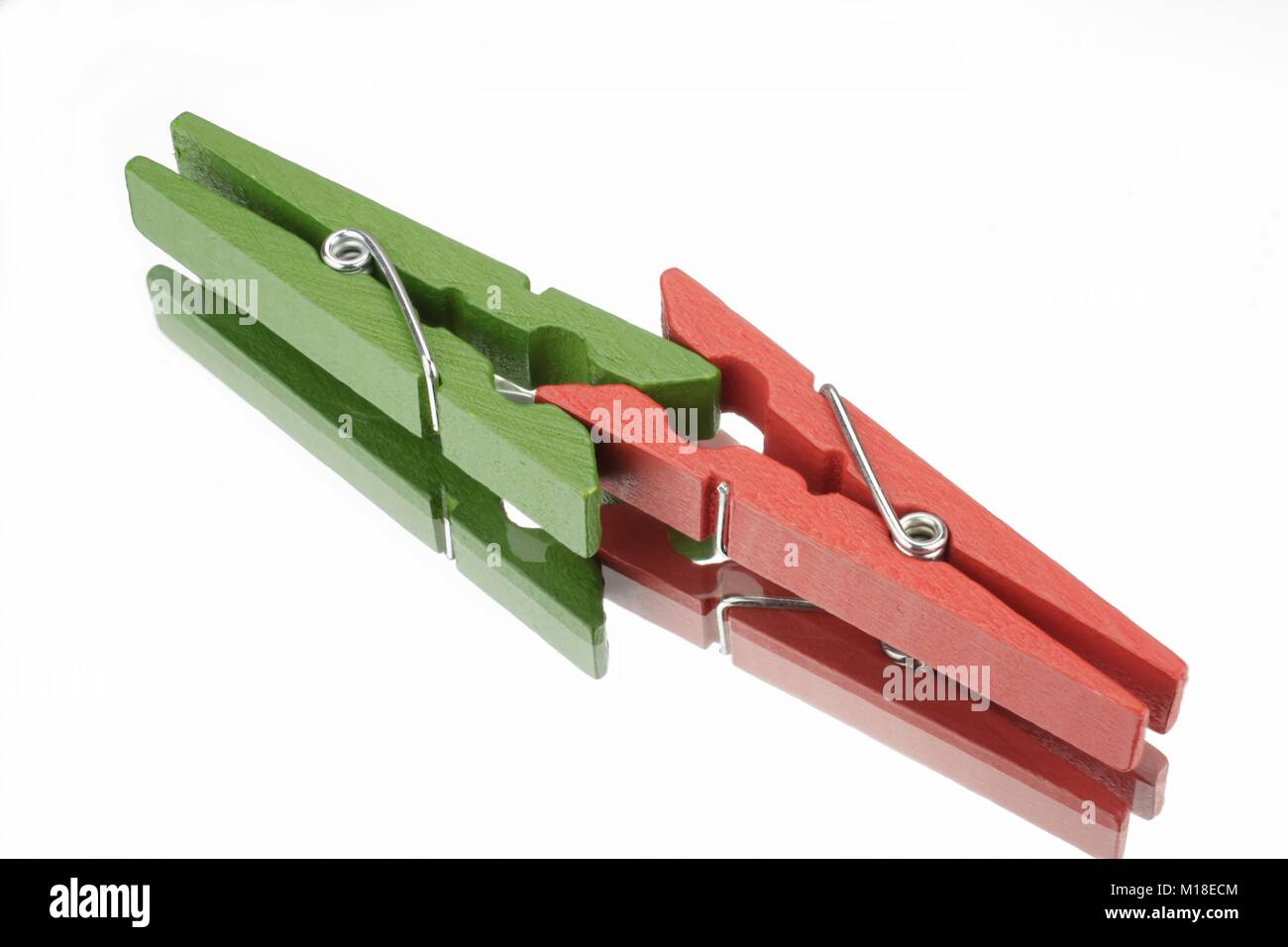 Il rosso e il verde clothespin davanti a uno sfondo bianco con riflessione speculare Foto Stock
