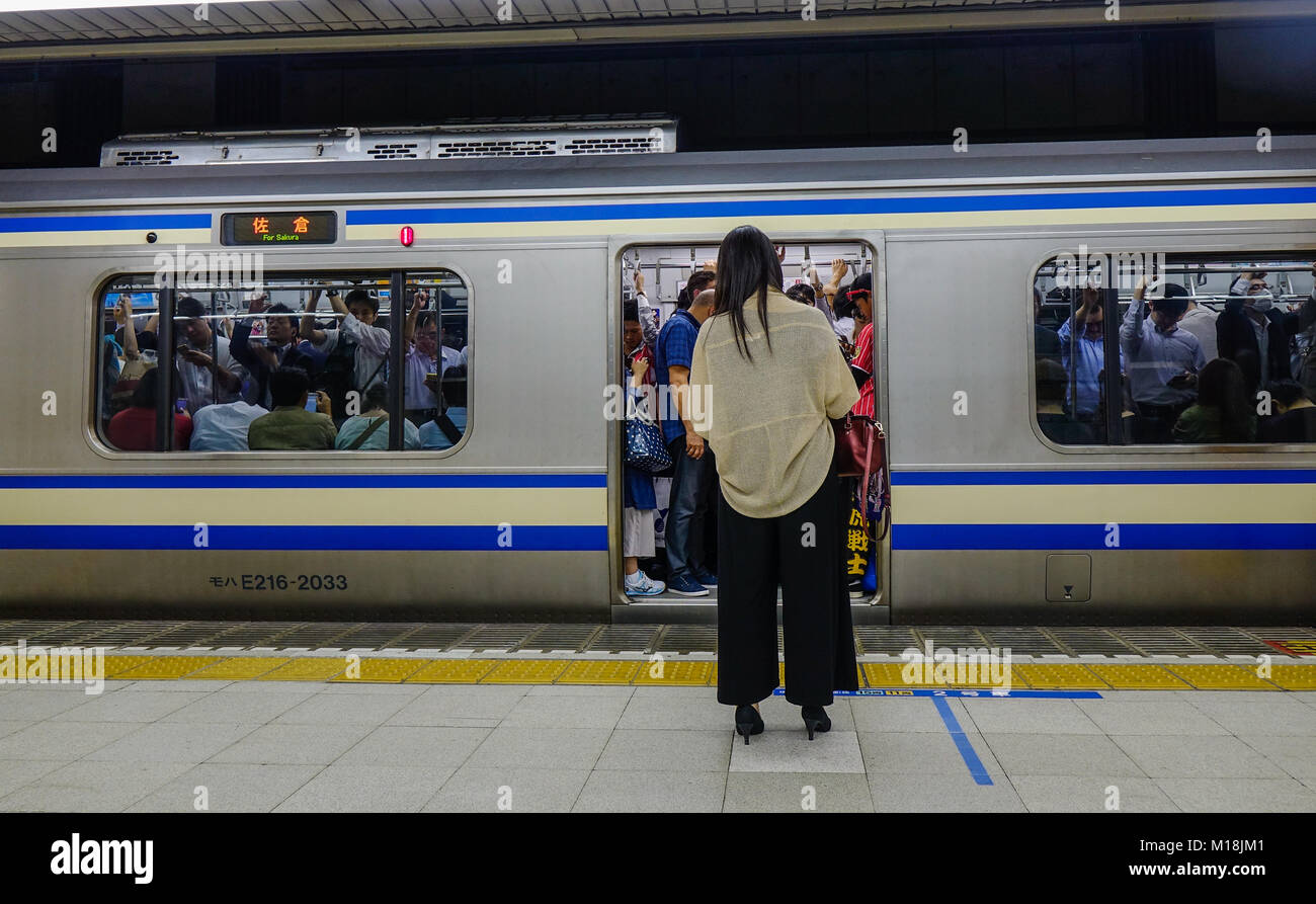 Tokyo, Giappone - 29 set 2017. Una donna in attesa del treno alla stazione principale a Tokyo in Giappone. Il trasporto ferroviario in Giappone è uno dei principali mezzi per il trasporto di passeggeri tran Foto Stock