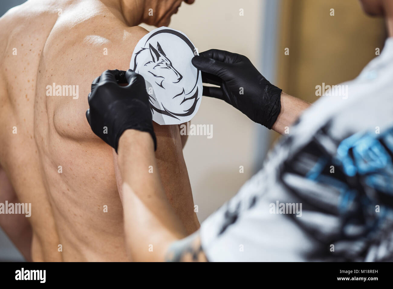 Master tattooist rende un tatuaggio sulla pelle del client con equipaggiamento speciale Foto Stock