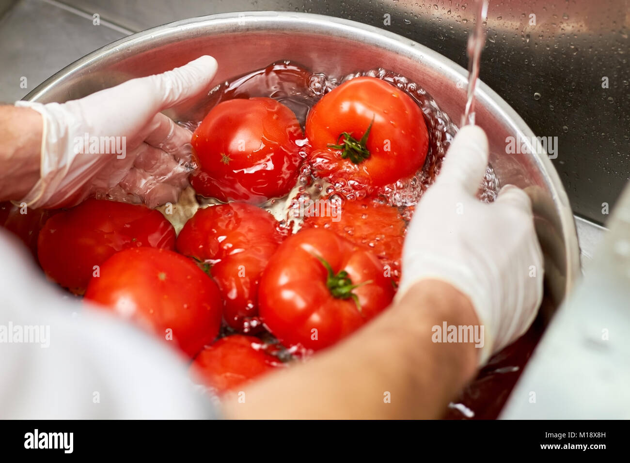Il lavaggio di grossi pomodori rossi nella ciotola. Foto Stock