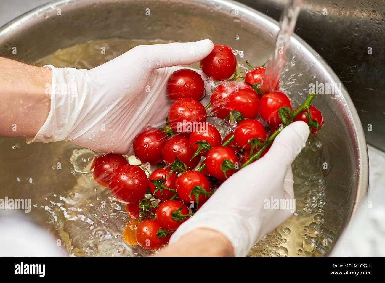 Lo Chef mani tenendo il vapore collegato i pomodori ciliegia. Foto Stock