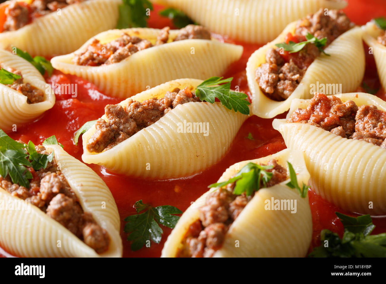 Guscio di pasta conchiglioni con carne macinata ripieno in salsa marinara close-up nel piatto orizzontale. Foto Stock