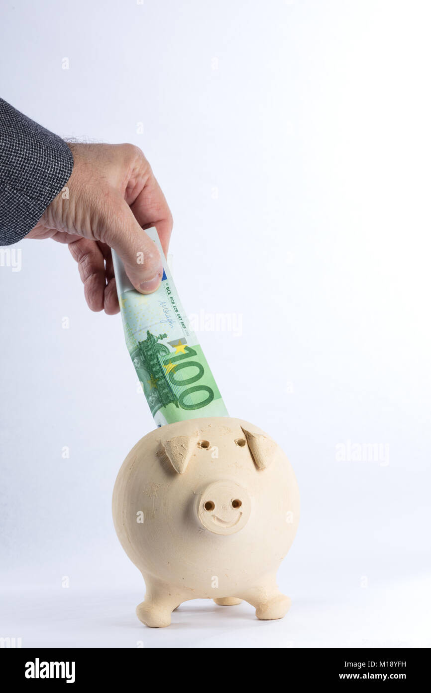 Una mano messa all'interno del salvadanaio di risparmio, di colore giallo, 100 euro su uno sfondo bianco. Spazio libero per il testo Foto Stock