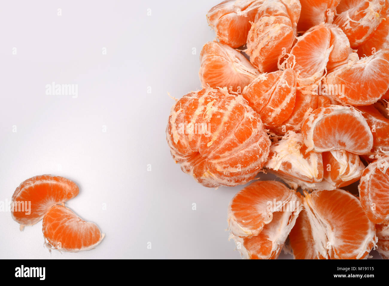 Orange appena sbucciata fette di mandarini con venature bianche su sfondo bianco, sulla sinistra si trovano due strati separati, uno spazio vuoto per il testo in Foto Stock