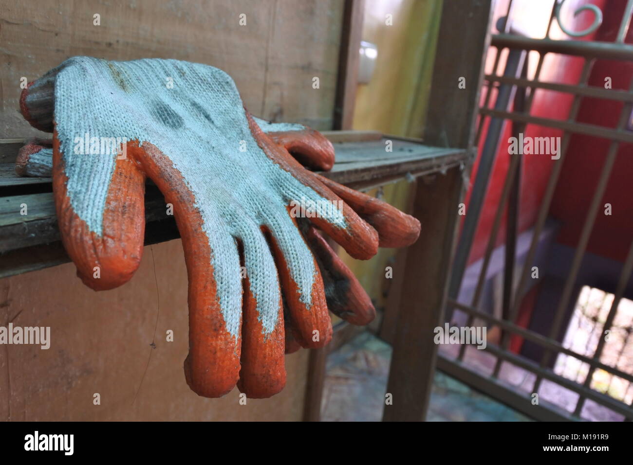 Un usato industriale di gomma Guanti palm seduto su un vecchio woody mobili. Foto Stock