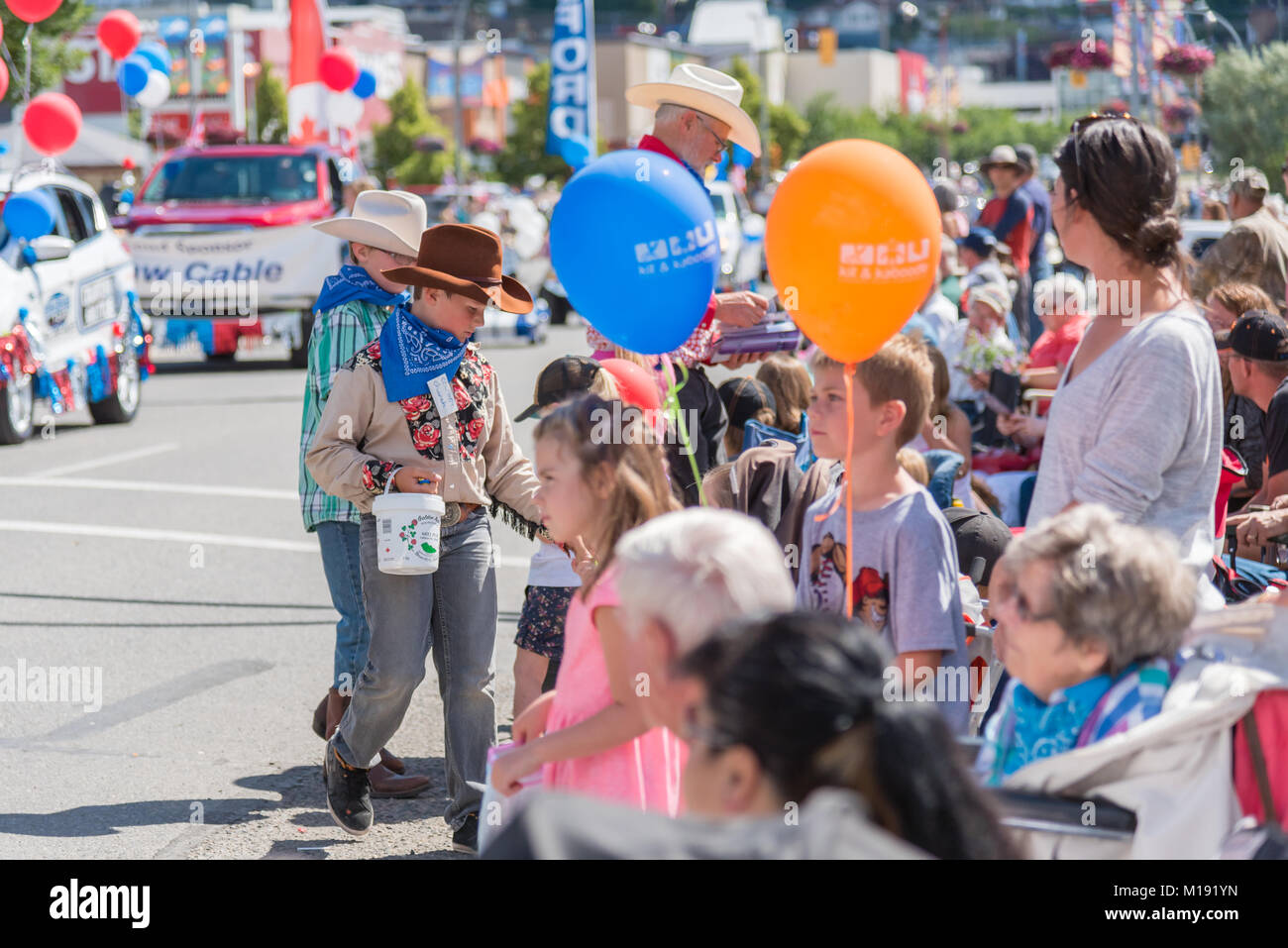 I bambini vestiti da cowboy fuori mano la caramella per guardare la gente la Stampede annuale parata nel centro di Williams Lake, durante la Williams Lake Stampede. Foto Stock