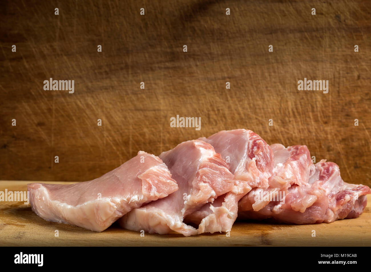 Fette di carne fresca di suino controfiletto sul tagliere di legno Foto Stock