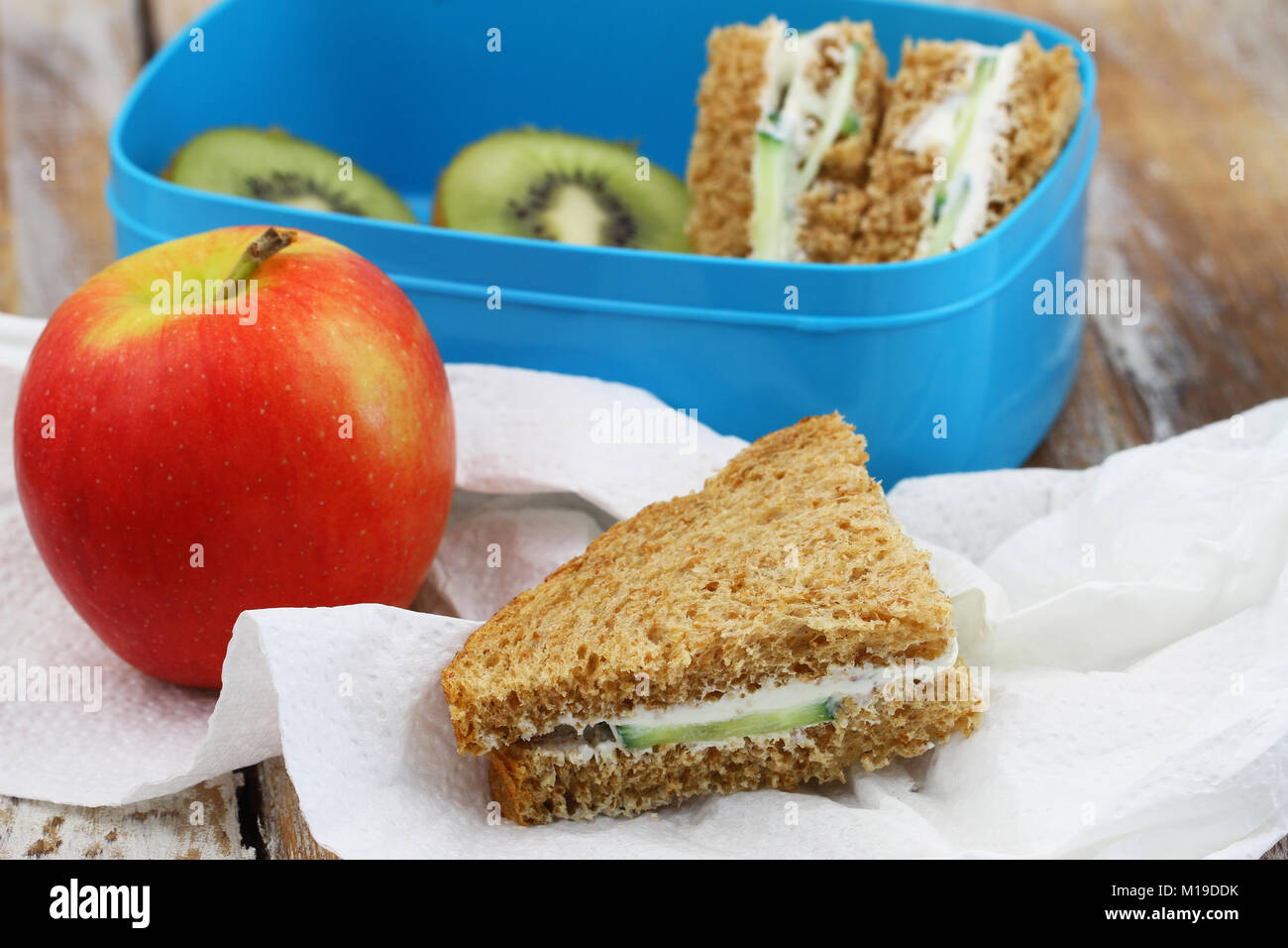 Un sano pranzo composto da marrone a crema di formaggio panini, kiwi e mela rossa Foto Stock