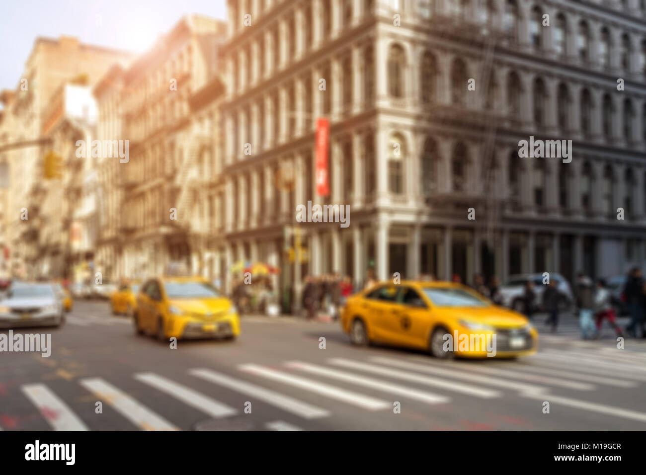 I taxi di guida attraverso l'intersezione a Broadway con una folla di gente che lo shopping nel quartiere di Soho di New York City Foto Stock