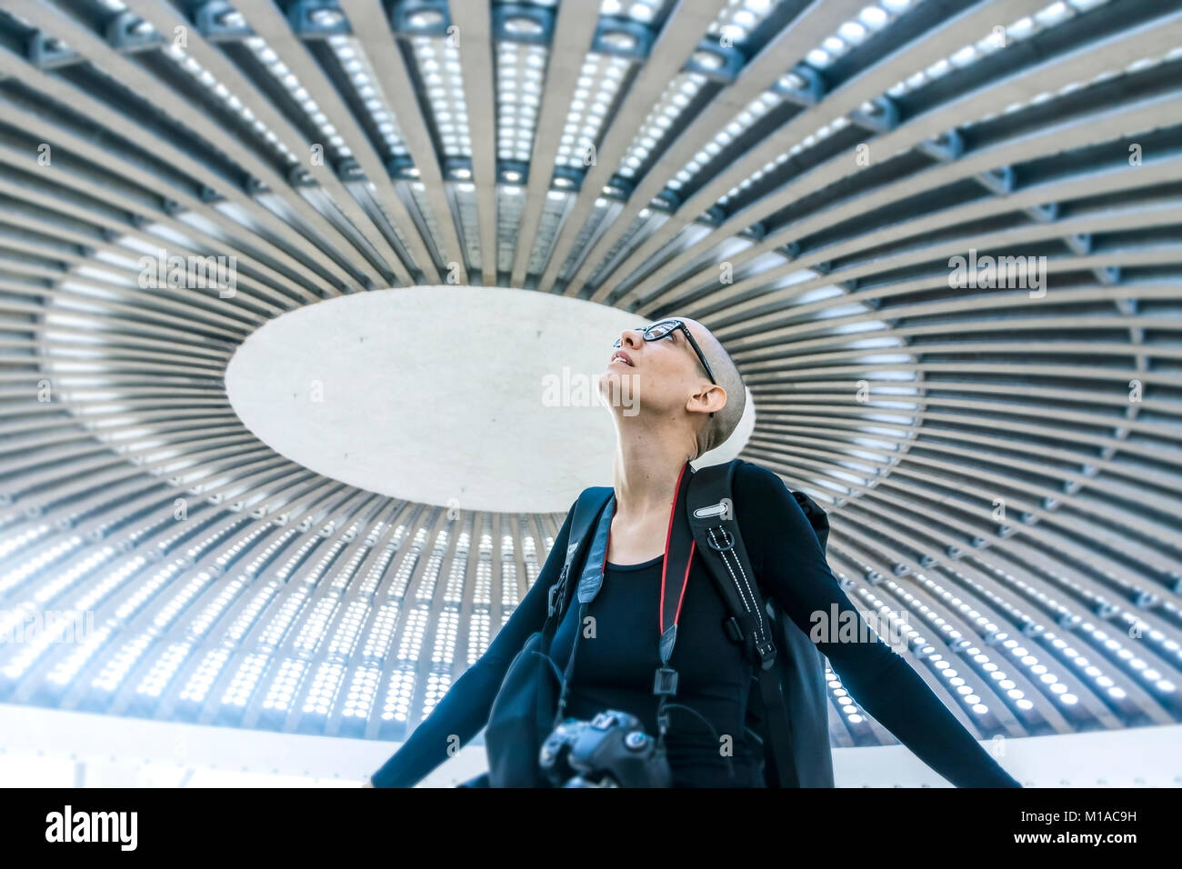 Un fotografo femmina ammirando una circolare enorme sala da concerto soffitto Foto Stock