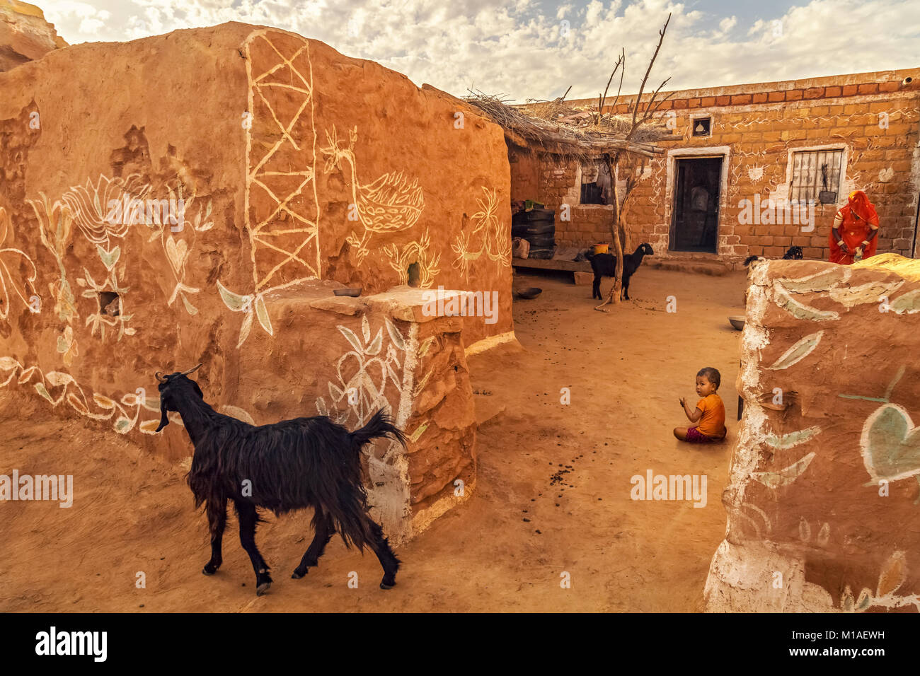 Il villaggio di Rajasthani vicino al deserto di Thar Jaisalmer con mattoni di fango villaggio di case di capre e un bambino. Foto Stock