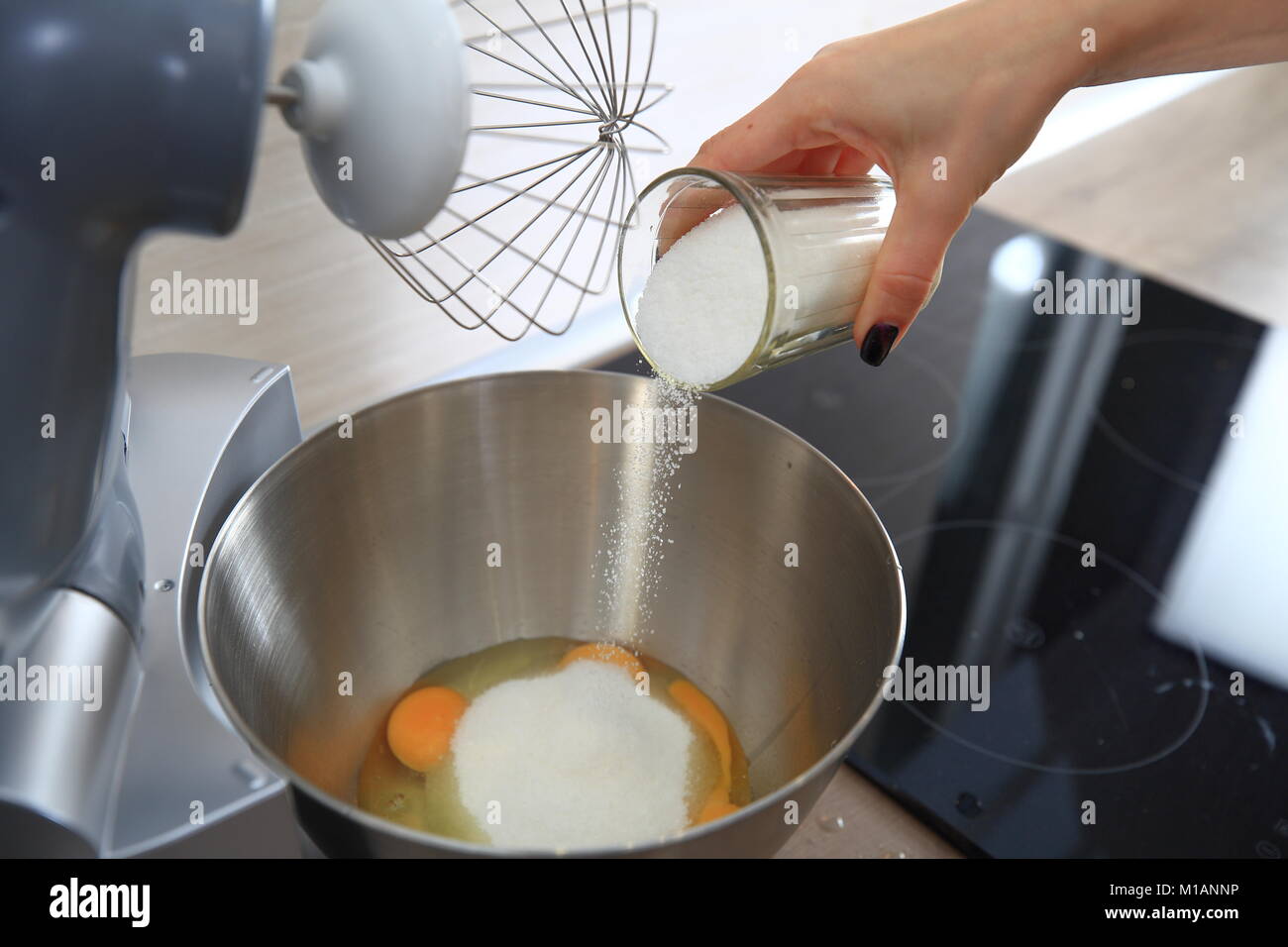 La donna la cottura di una torta. La casalinga si aggiunge lo zucchero nel recipiente del robot da cucina. Foto Stock