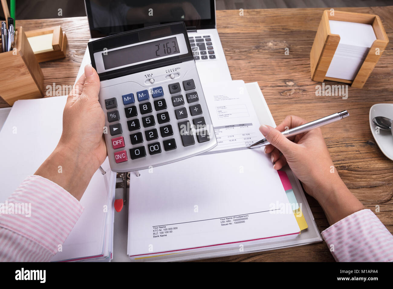 Imprenditrice Calcolatrice tenendo in mano il calcolo di fattura sulla scrivania Foto Stock