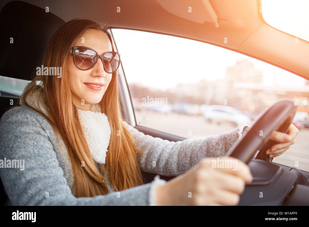 Giovane donna guidare un auto in inverno. Sorridente donna europea volante all'interno di un automobile Foto Stock