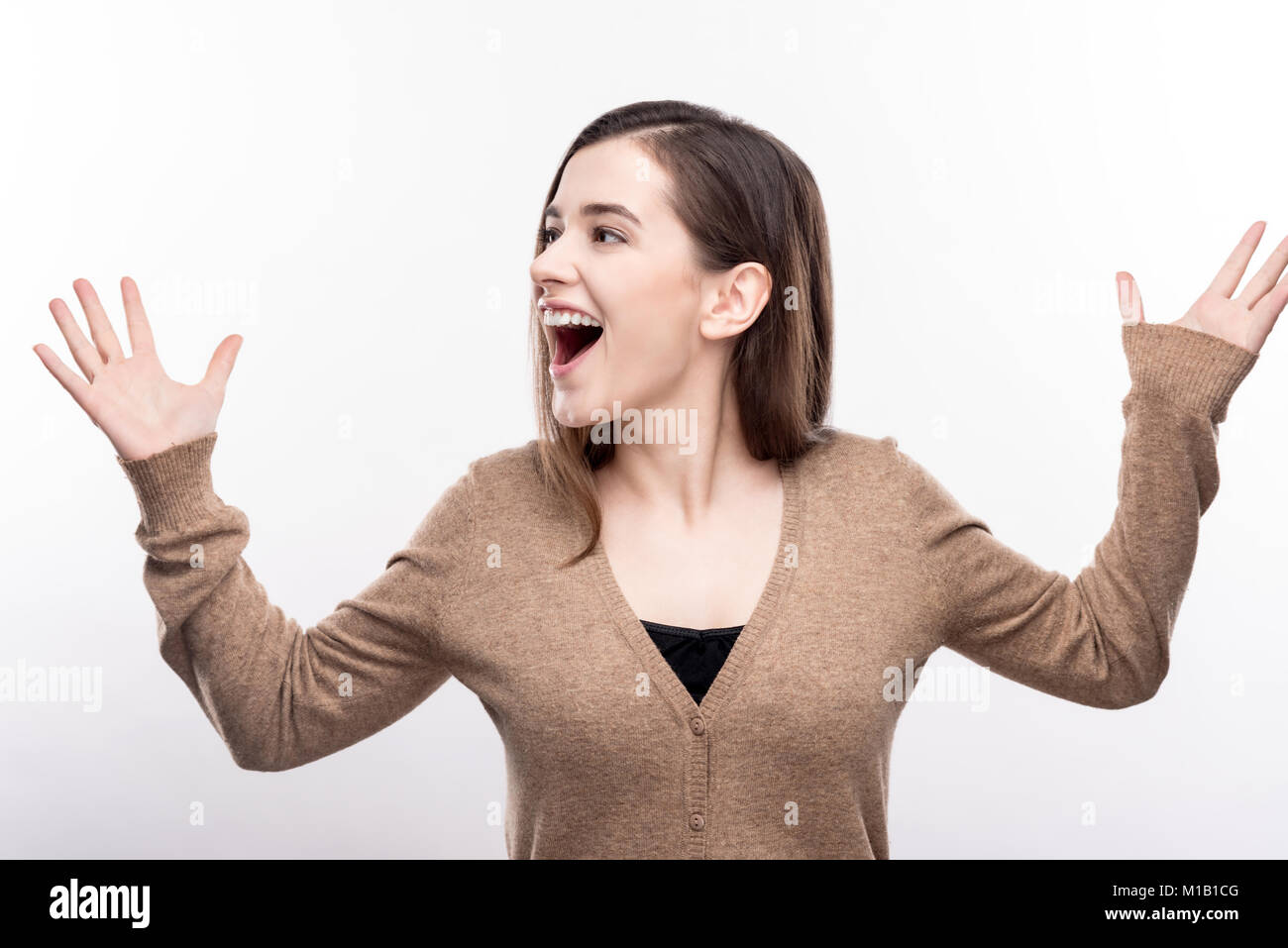 Piacevole donna gridando gioiosamente e alzando le mani Foto Stock