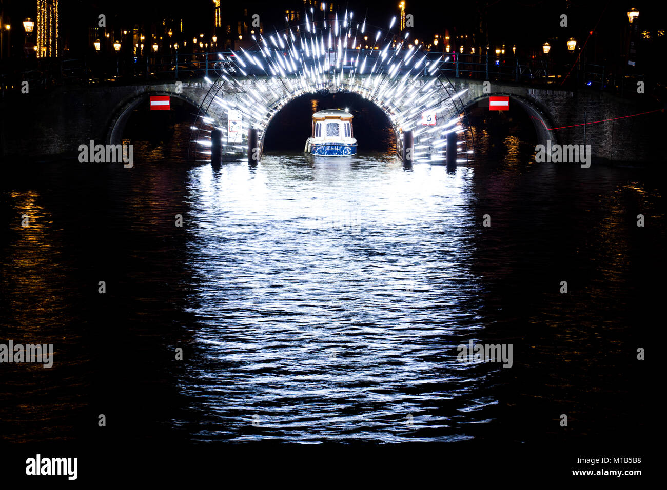 Una chiatta sul canale passa sotto un tunnel pieno di luci per il festival annuale di luce ad Amsterdam in Olanda. Foto Stock