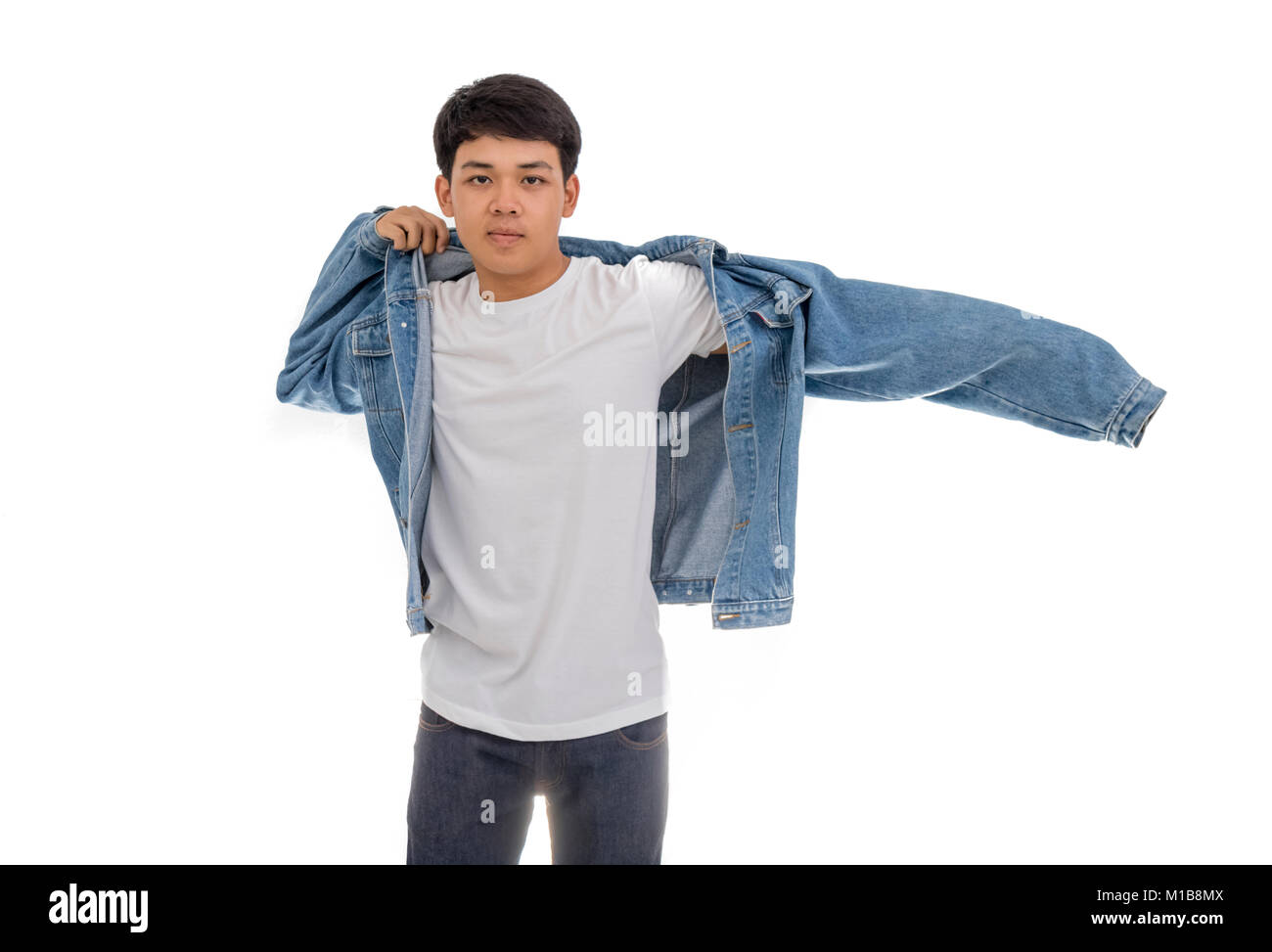 Un ragazzo asiatico con i capelli neri mette in studio con una camicia bianca e jeans giacca. Foto Stock