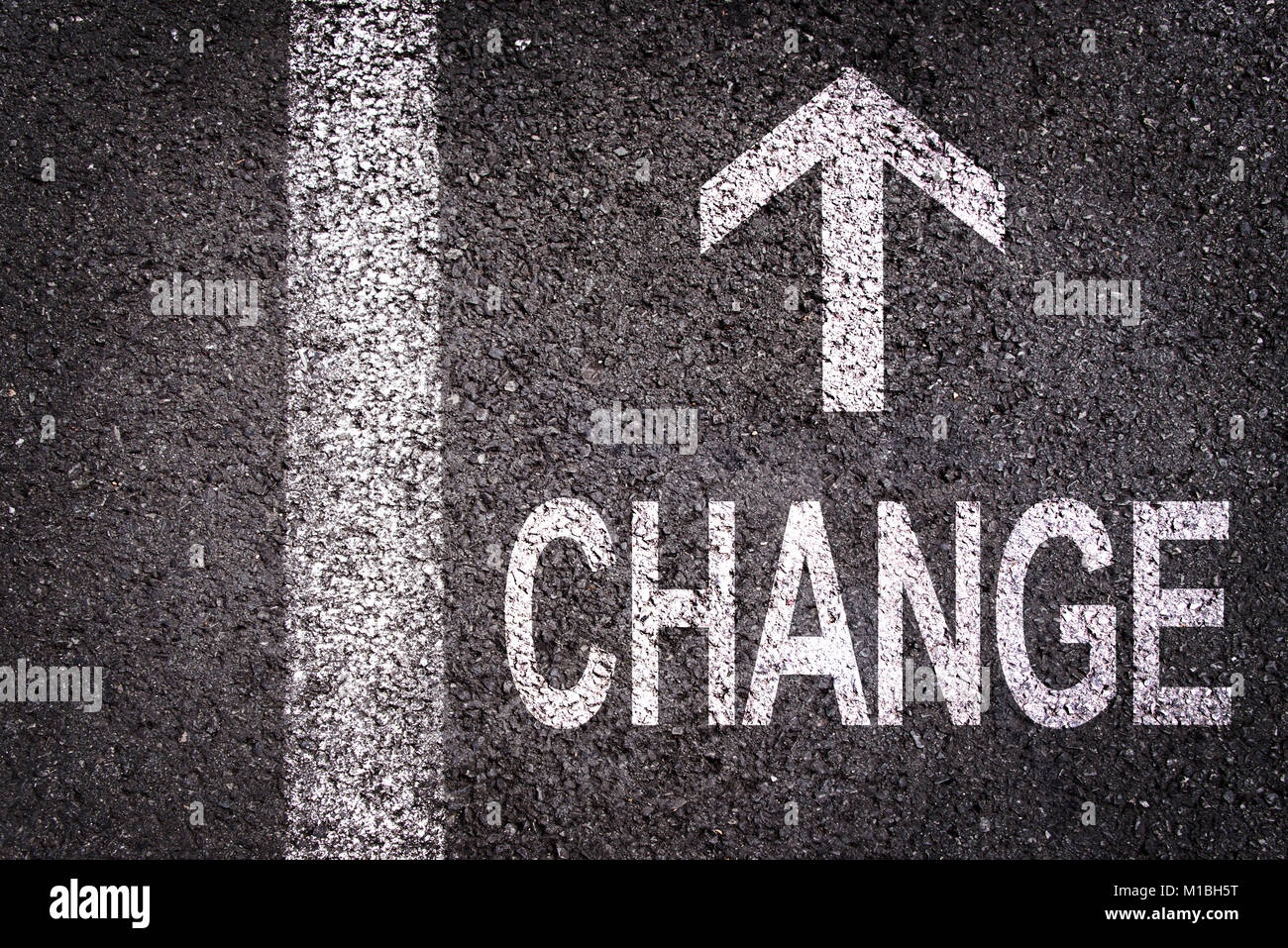 Parola di cambiare e una freccia scritto su una strada asfaltata in background Foto Stock