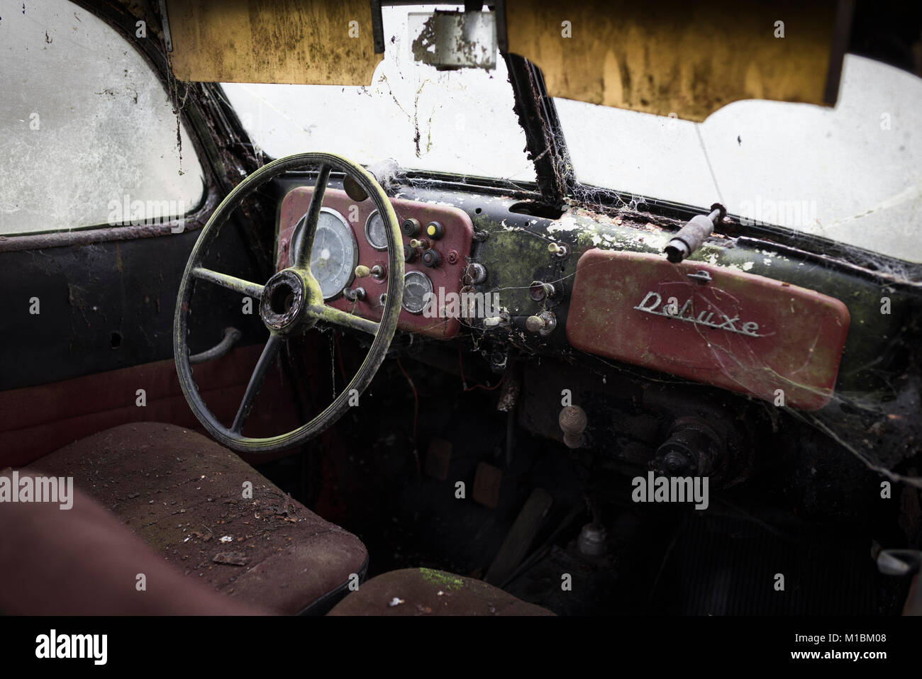 Interno di un abbandonato arrugginimento classic car con volante di guida e strumenti Foto Stock