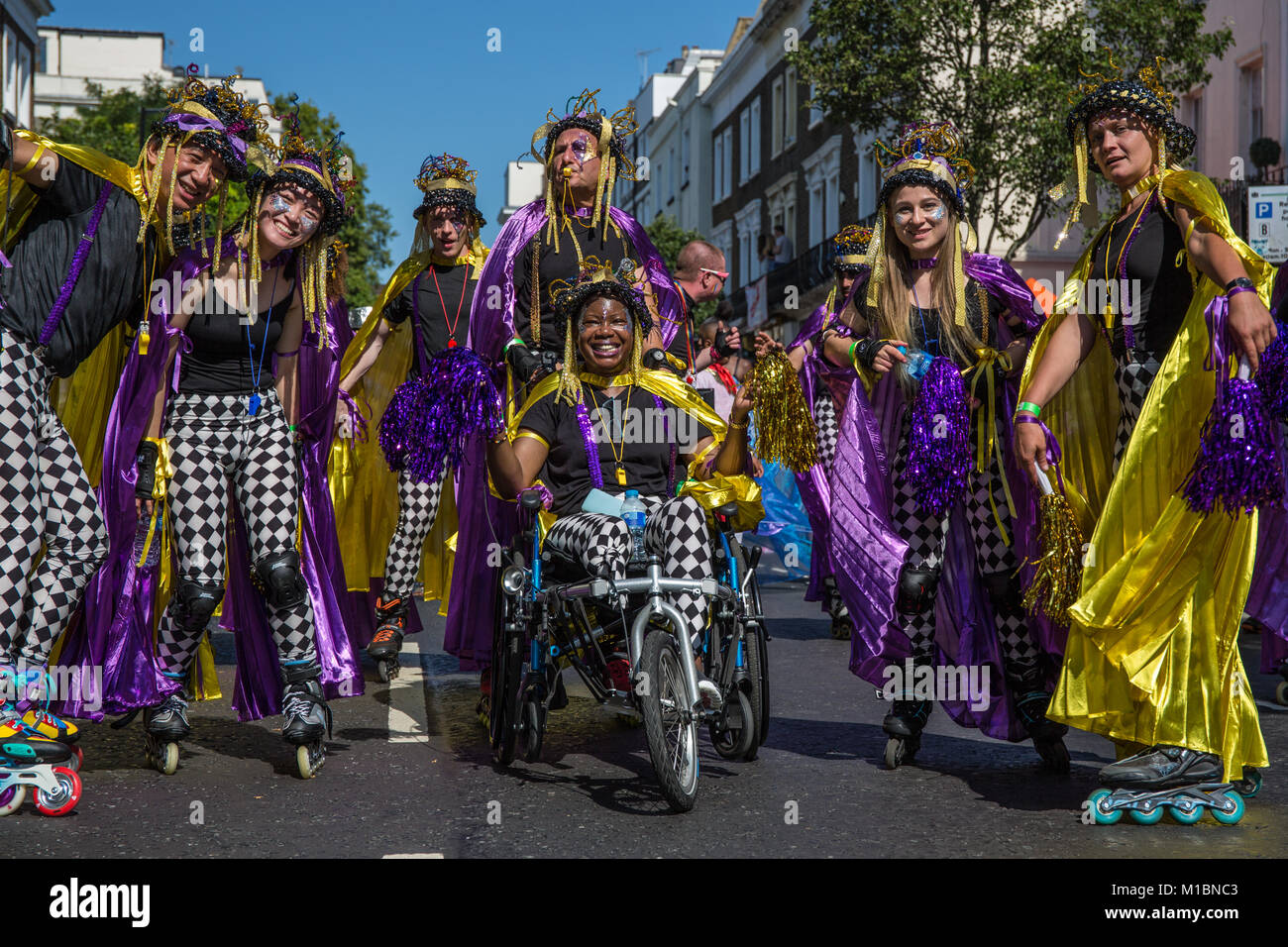 Gruppo di pattinatori in oro giallo e viola i costumi al carnevale di Notting Hill, London, Regno Unito Foto Stock