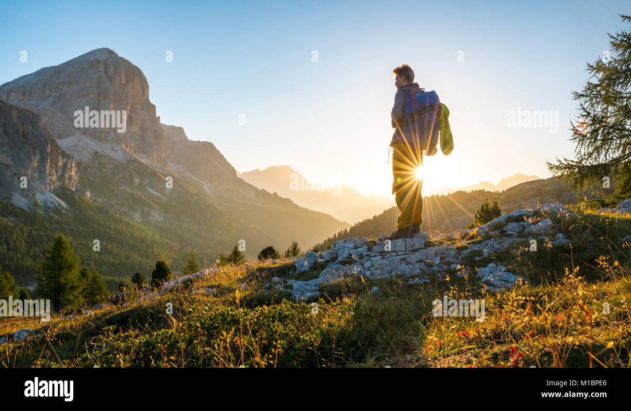 Escursionista guardando in lontananza, sunrise, solare riflesso nella parte anteriore del Col dei Bos e Tofane picchi, Passo Falzarego, Dolomiti Foto Stock