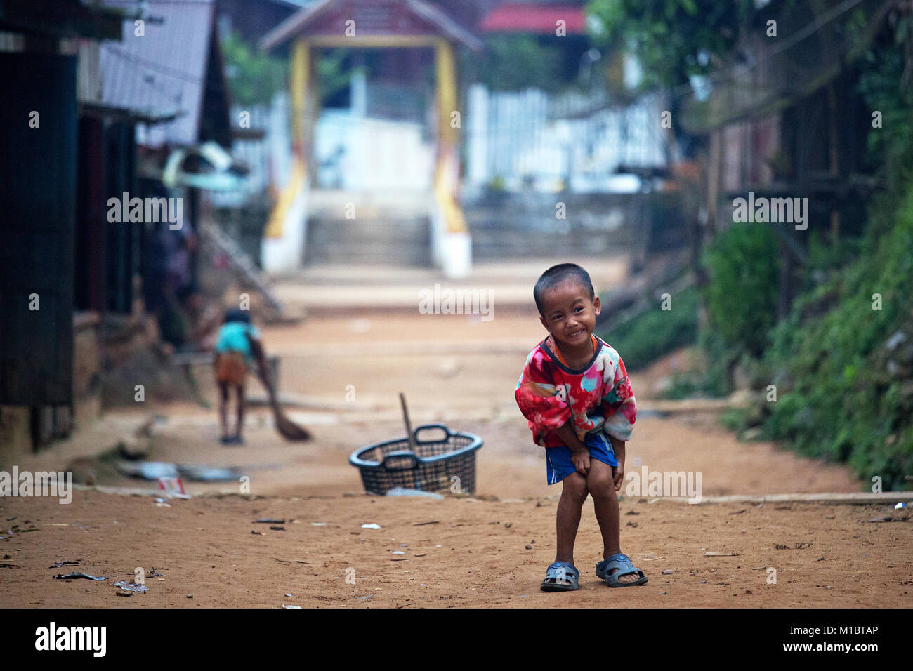 Giovane ragazzo davanti al tempio di divieto remoto Hat Sa Village, Nord del Laos, Asia Foto Stock