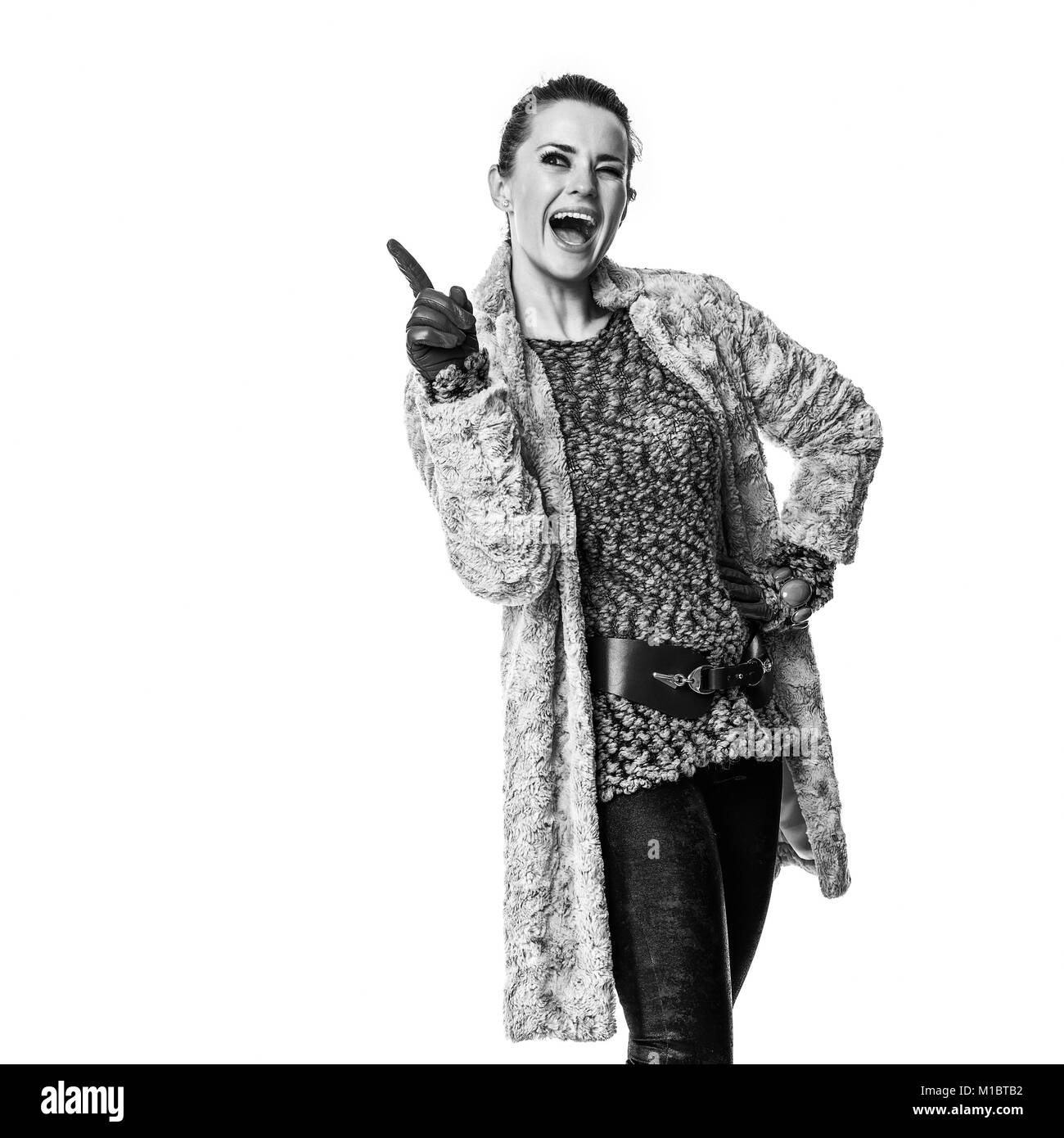 Cose d'inverno. A piena lunghezza Ritratto di sorridente giovane donna in cappotto invernale isolato su bianco rivolto verso qualcosa di Foto Stock