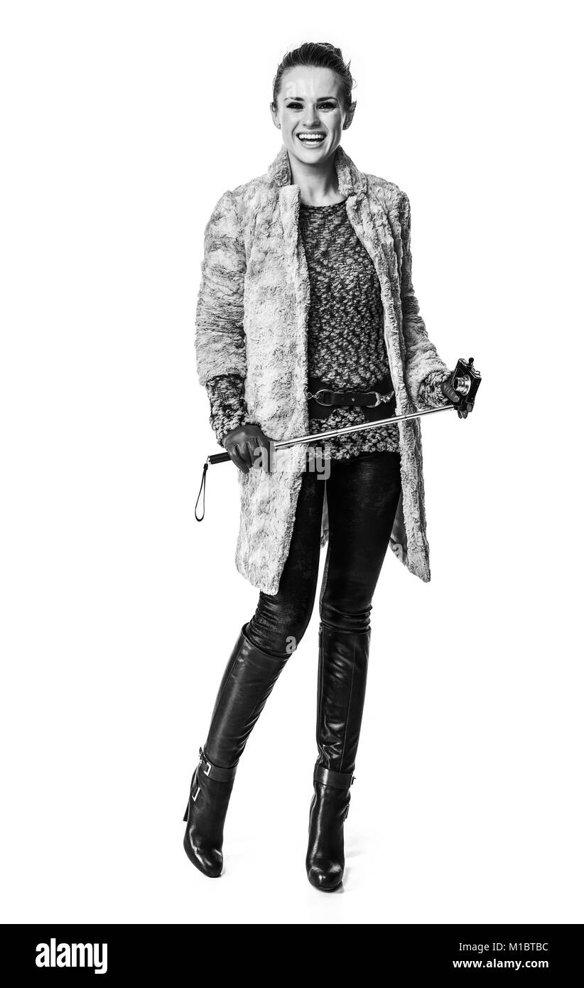Cose d'inverno. A piena lunghezza Ritratto di sorridere alla moda-monger in cappotto invernale isolato su bianco con selfie stick Foto Stock
