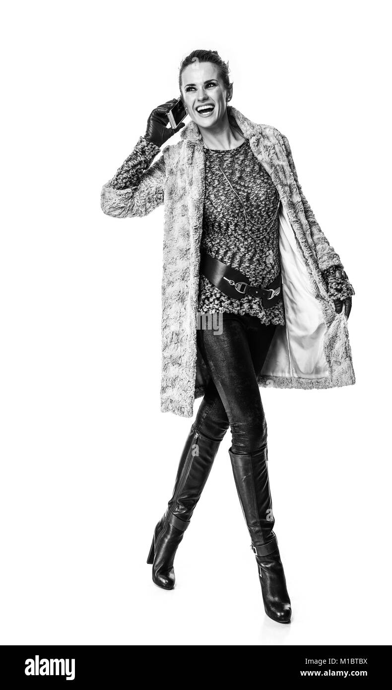 Cose d'inverno. A piena lunghezza Ritratto di sorridere alla moda donna in cappotto invernale isolato su bianco utilizzando uno smartphone e passeggiate Foto Stock