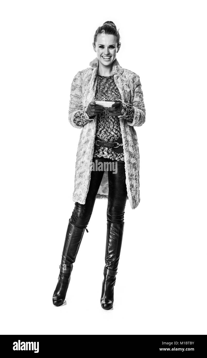 Cose d'inverno. A piena lunghezza Ritratto di sorridere moderna moda-monger in cappotto invernale isolato su bianco la scrittura di sms Foto Stock